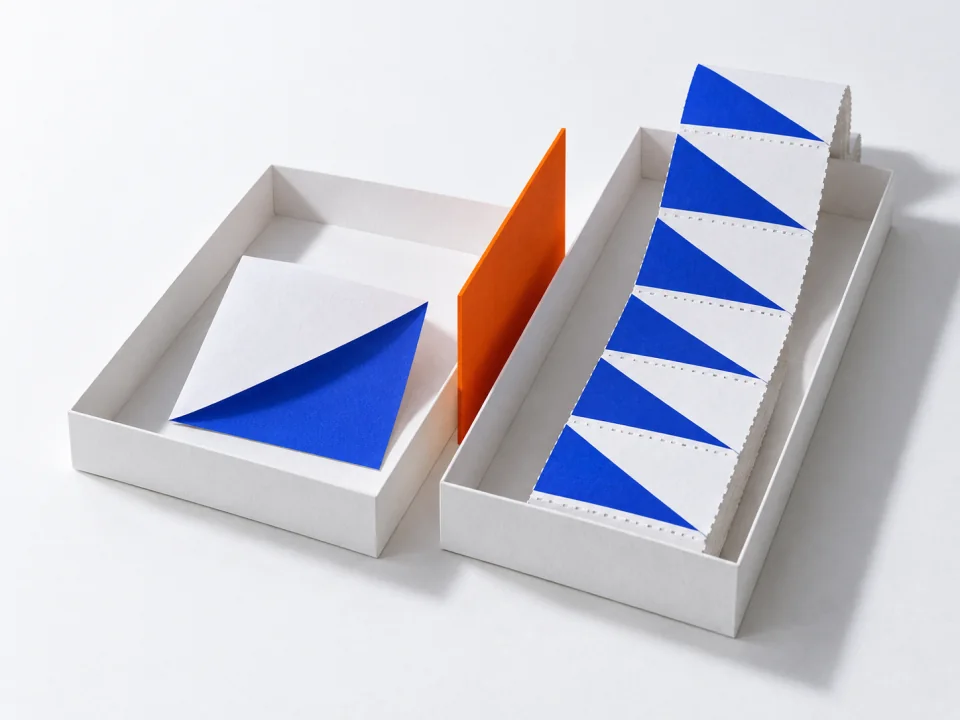 A folded note and a perforated strip of slips on separate trays, an orange divider between them.