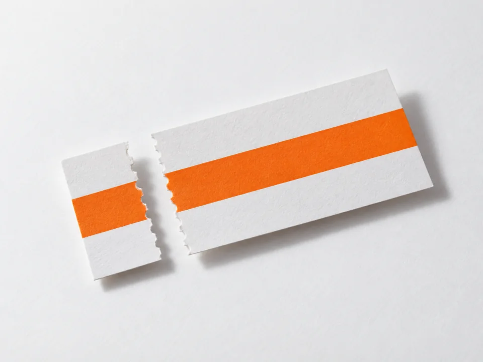 A paper slip and its perforated stub, their orange bands lining up across a gap.