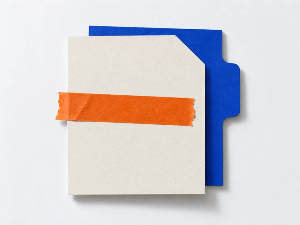 A blank form card sealed with orange tape over a cobalt card whose tab points right.