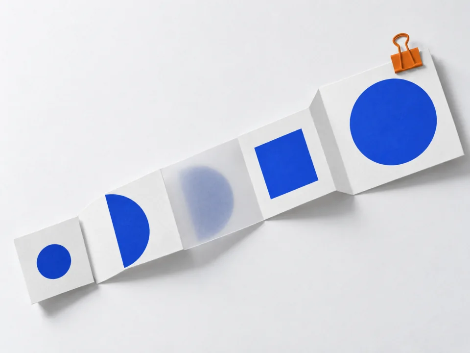 A long folded paper strip from a small card to a larger card held by an orange clip.