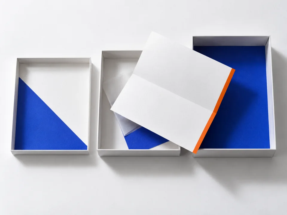 A folded letter with an orange edge resting across the rims of three paper trays.